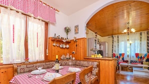 A cozy dining area with a checkered tablecloth, wooden chairs, and a bottle of wine. - Apartment Giuseppe (Mali Losinj)