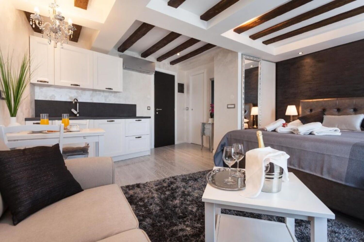 Une chambre d’hôtel moderne équipée d’un lit, d’une table de chevet et d’un petit coin salon avec un canapé et une table.