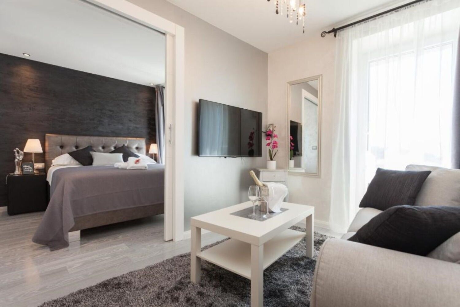 A modern bedroom with a bed, bedside table, and a large mirror.