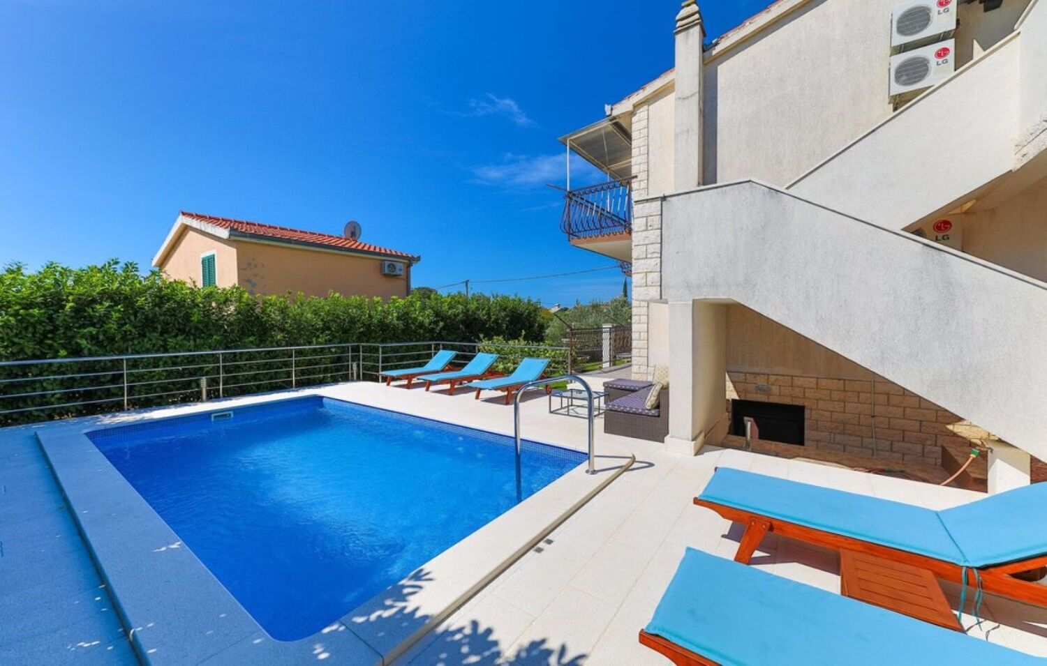 Ein Pool mit Liegestühlen, einer Grillgegend und Blick aufs Meer.