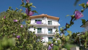 A multi-story building with balconies, surrounded by greenery and flowers. - Apartments Gloria (Gradac)