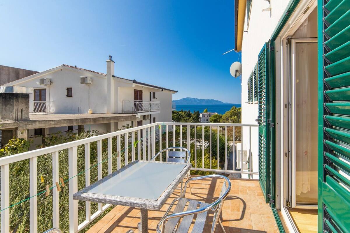 En balkon med et bord og en stol, der ud til et boligområde og et bjerg.