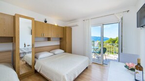 A bedroom with a bed, wooden wardrobe, and a balcony with a table and chairs. - Apartments Gloria (Gradac)