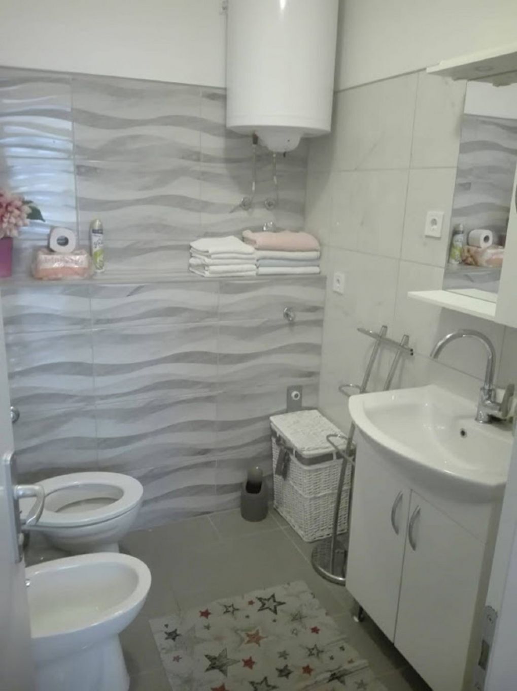 A bathroom with a toilet, bidet, sink, and a towel rack.