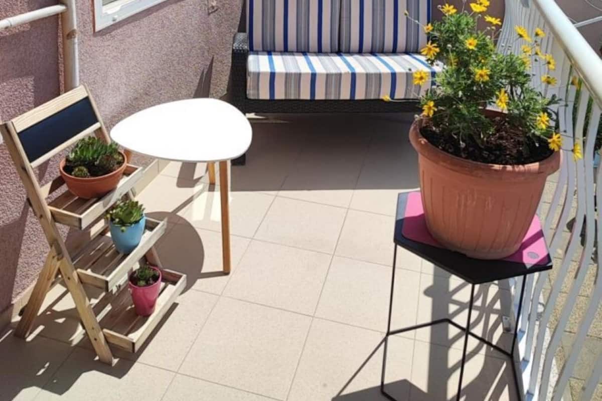 A balcony with a striped sofa, a small round table, and potted plants.