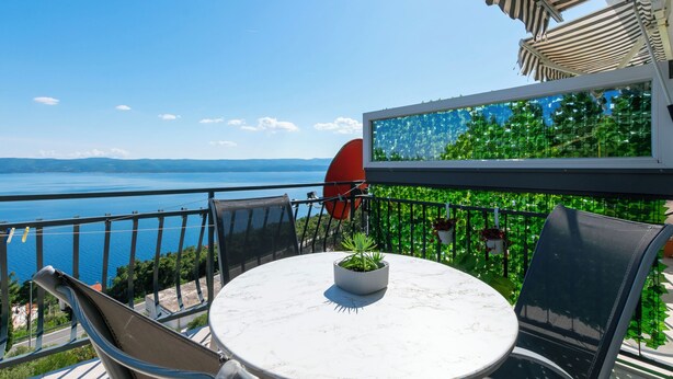 A terrace with a round table, chairs, and a potted plant. - Apartments Zorica (Omis)