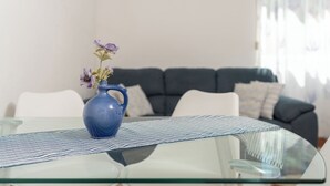 Ein Glastisch mit einer blauen Vase, in der violette Blumen stehen.
