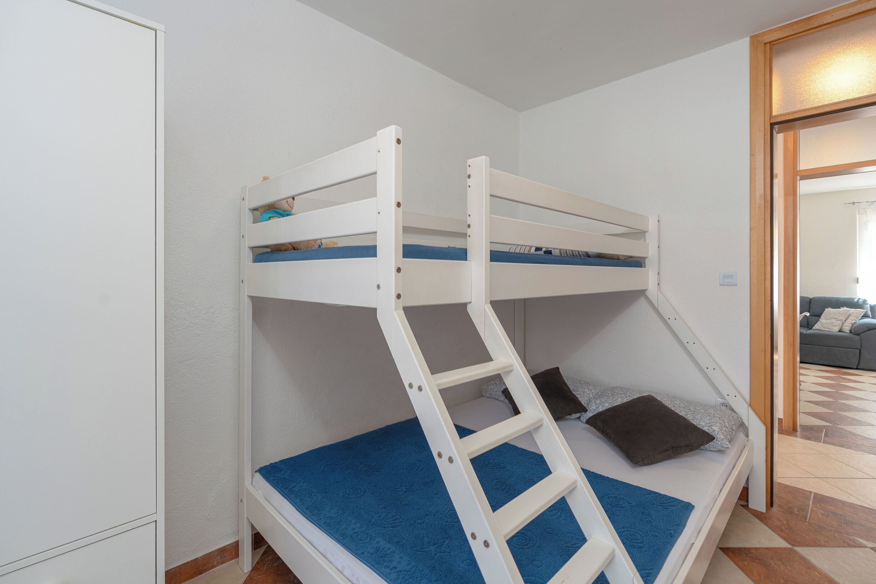 Una cama litera con escalera, un colchón azul y una almohada marrón.