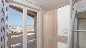 Ein Zimmer mit einer Schiebeglasdoor zum Balkon, einem Stockbett und einer Holzwand.