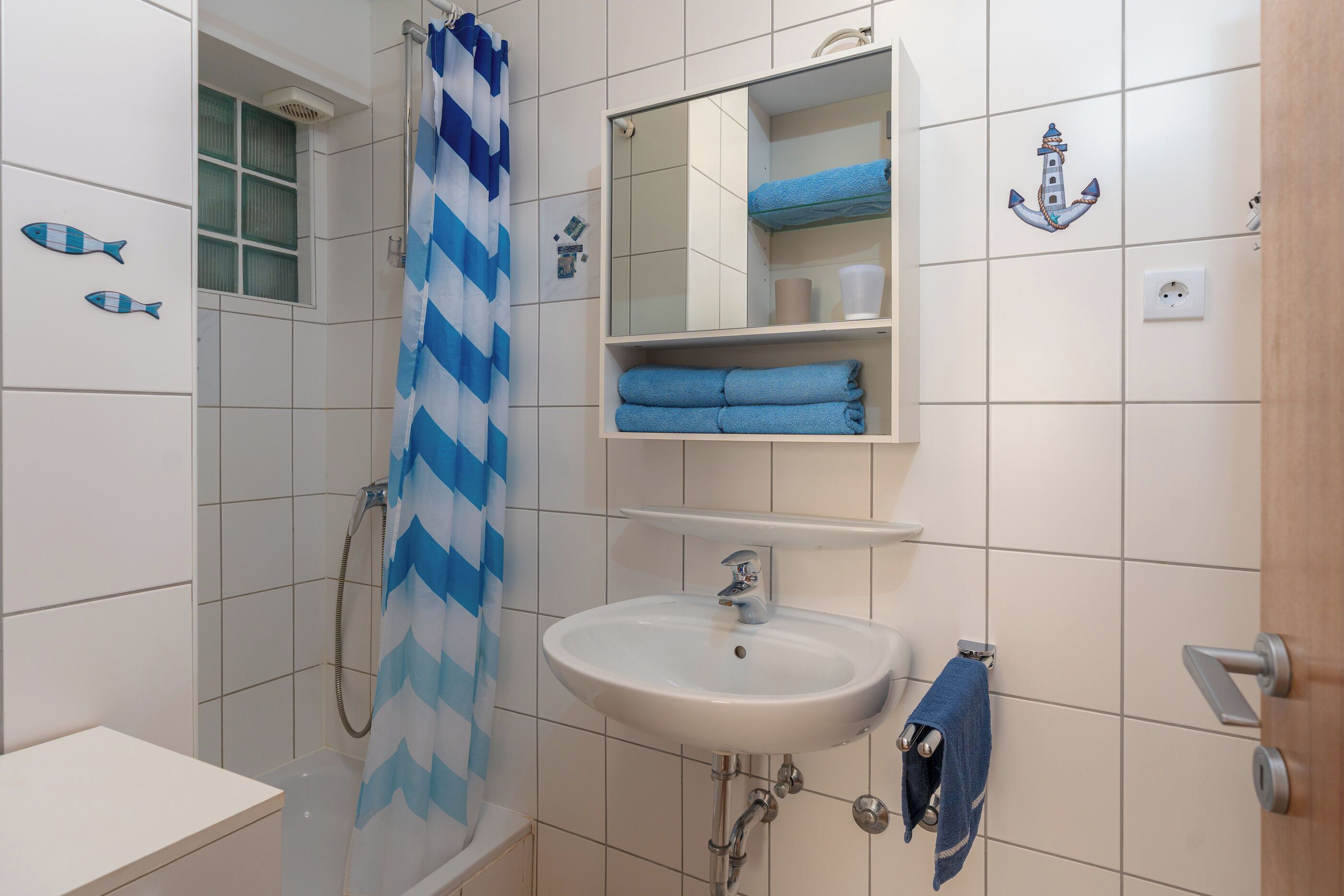 Un baño con ducha, lavabo, espejo y toallero.