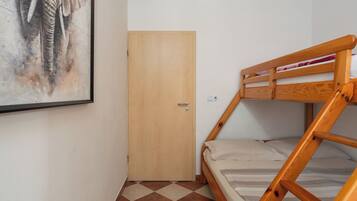 Una stanza piccola con un letto a castello, una porta di legno e un quadro appeso al muro.