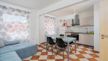 A compact living space with a sofa, dining table, chairs, and a kitchen area.