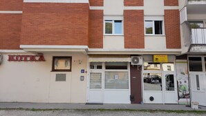 Ein Gebäude mit einem 'KOTKA'-Schild, einem 'JAGODA'-Salon und einem 'RIZBERSKI SALON' im Erdgeschoss.