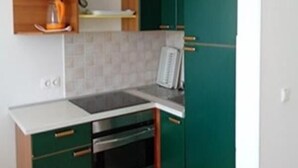 Una cucina compatta con mobili verdi, un piano di lavoro bianco e un forno integrato.