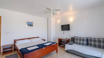 Ein Hotelzimmer mit einem Bett, einem Sofa, einem Fernseher und einem Deckenventilator.