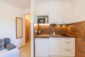 A compact kitchenette with a built-in microwave, a kettle, and a sink. - Apartments Vlado (Omisalj)