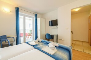 A hotel room with a bed, a desk, a chair, a television, and a bathroom. - Apartments Vlado (Omisalj)