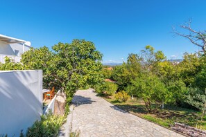 Un vialetto in pietra che si snoda attraverso un giardino con alberi e vista sul paesaggio.