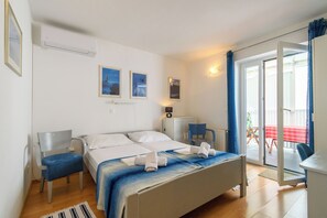 A hotel room with a bed, a chair, a desk, and a view of the outside. - Apartments Vlado (Omisalj)
