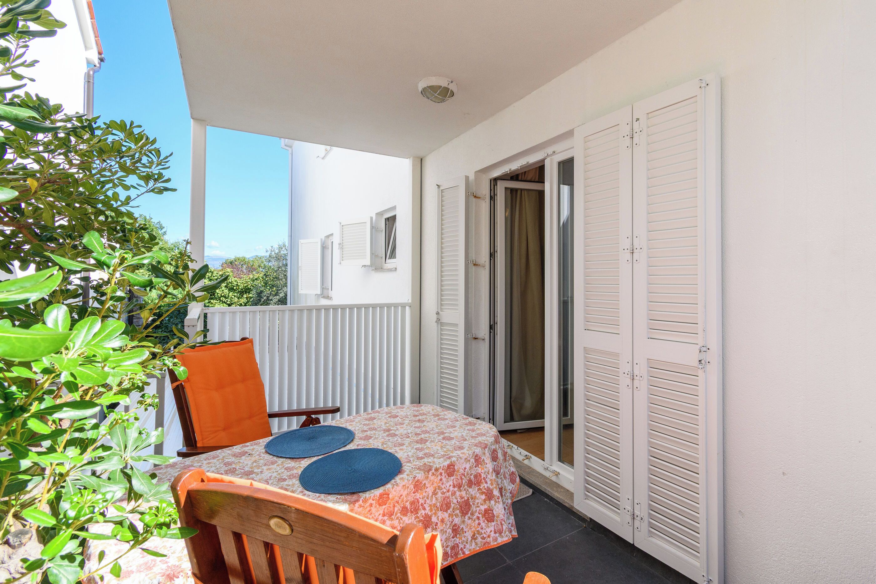 Un balcon avec une table, des chaises et une vue sur la mer.