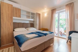 A bedroom with a bed, a wardrobe, a table, and a chair. - Apartments Vlado (Omisalj)
