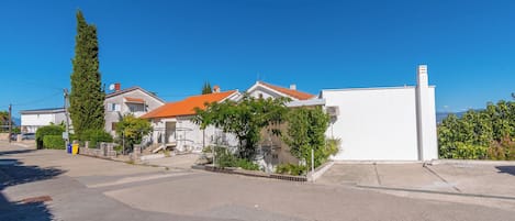 A residential street with houses, a clear sky, and a distant view of the sea.