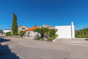 Una calle residencial con casas, cielo despejado y una vista distante del mar.