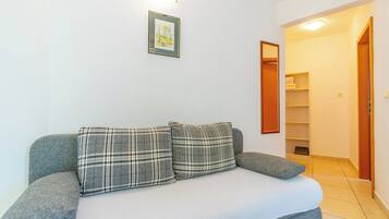 Ein Zimmer mit einem grauen Sofa, einem gerahmten Bild an der Wand und einer Holztür zu einem Flur.