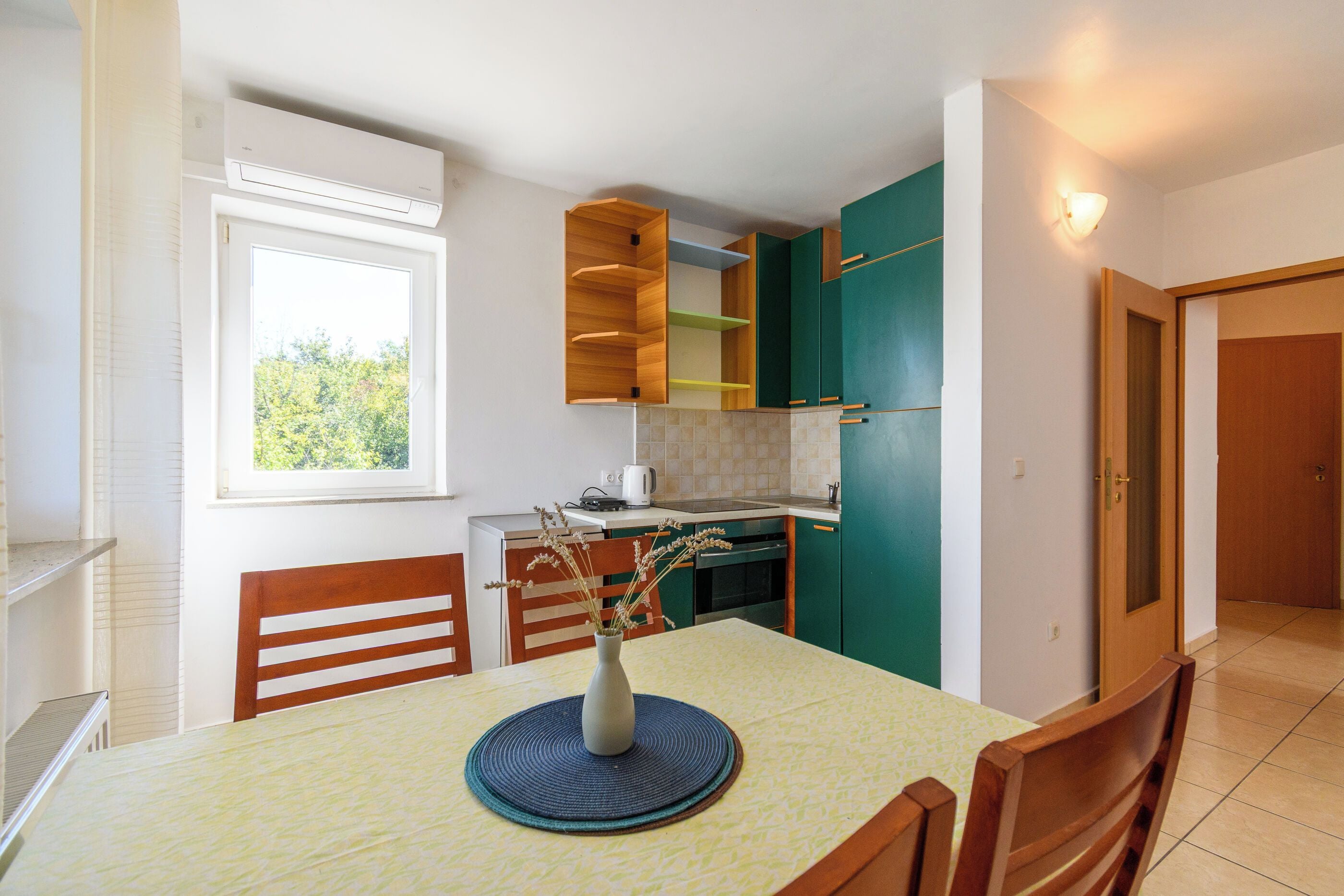 Una cocina compacta con una mesa de comedor, sillas, una cafetera y una ventana.