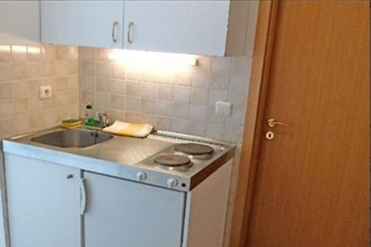 Un angolo cottura compatto con lavello, fornelli e pensili.