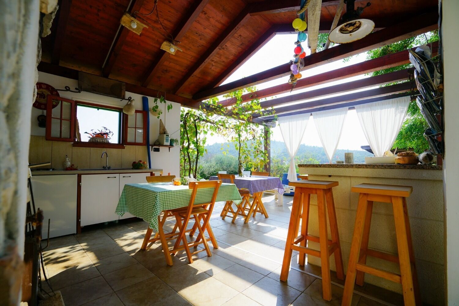 Une cuisine chaleureuse avec des meubles en bois, un coin repas avec une table et des chaises, et une vue sur la verdure à l’extérieur.