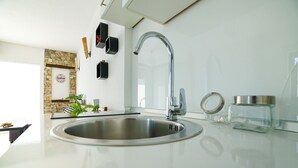 A modern kitchen with a stainless steel sink, a stone accent wall, and minimalist decor. - Apartments Secret Garden (Razanac)