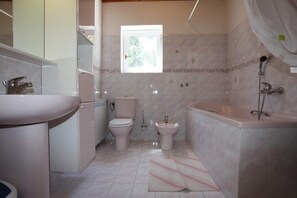 A bathroom with a toilet, bidet, and bathtub. - Apartments Nadi (Hvar)