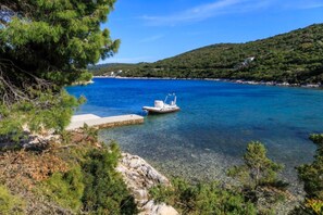 Una barca ormeggiata al molo, con acque cristalline e montagne sullo sfondo.