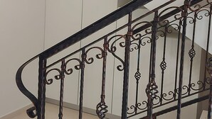 A staircase with ornate metal railings and a white wall in the background. - House DMS (Tisno)