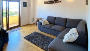 A modern living room with a grey sofa, a dark rug, and a cityscape painting on the wall. - House DMS (Tisno)