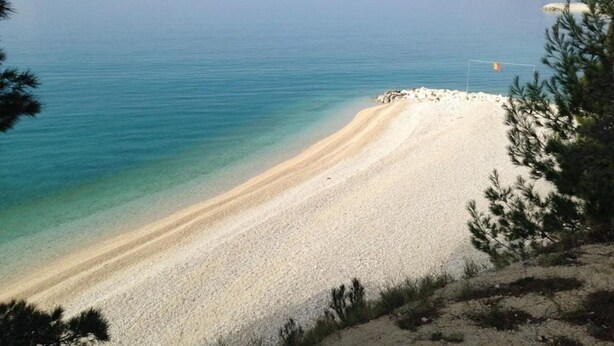 Ein Strand mit klarem Wasser und sandigem Ufer.