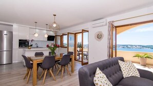 A modern apartment with a kitchen, dining area, and a living room with a sofa and a view of the sea. - Apartment Tom (Trogir)