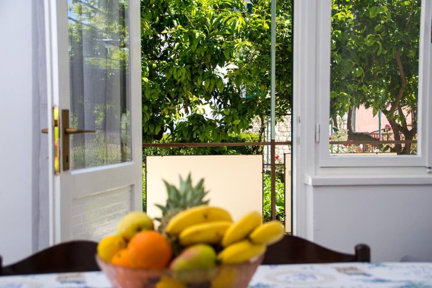 A room with a view of a balcony and a table with a fruit bowl.