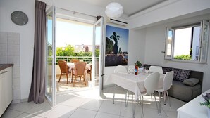 Een modern appartement met een eethoek, een bank en een balkon met buitenmeubilair.