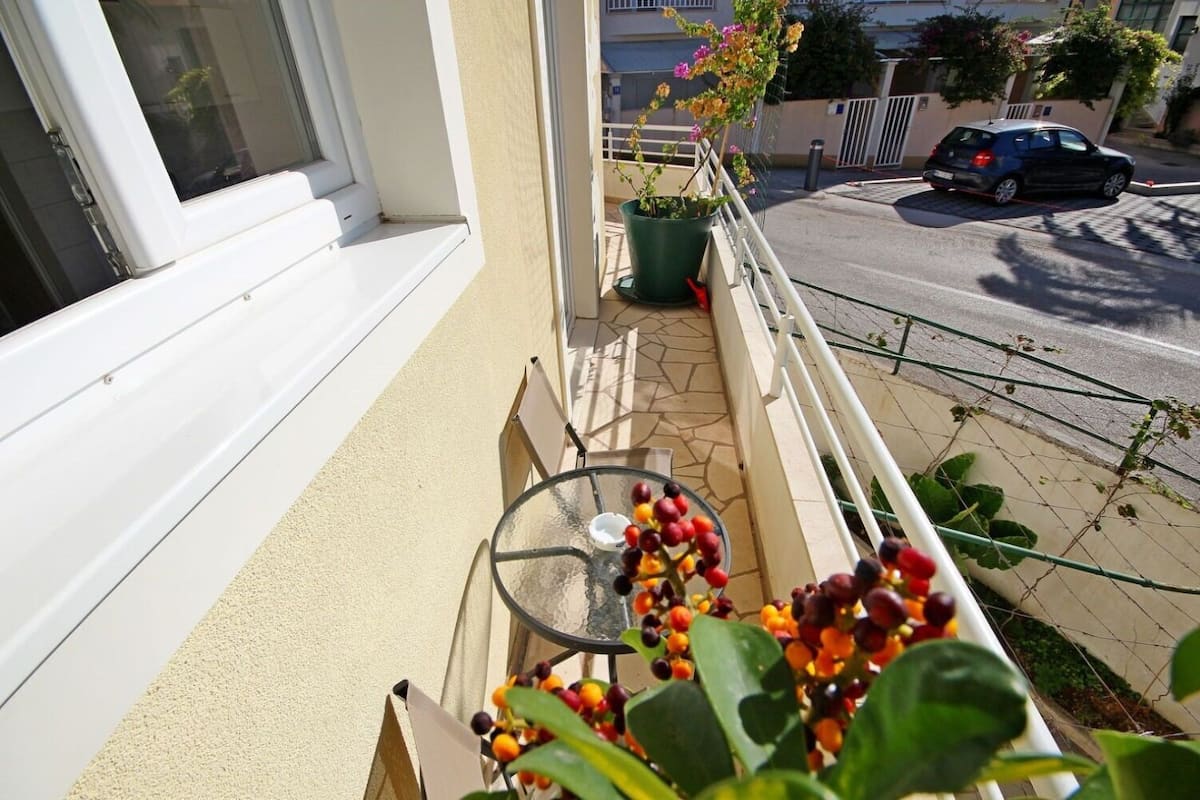 Ein Balkon mit einem kleinen Tisch, einem Blumentopf und Blick auf die Straße.