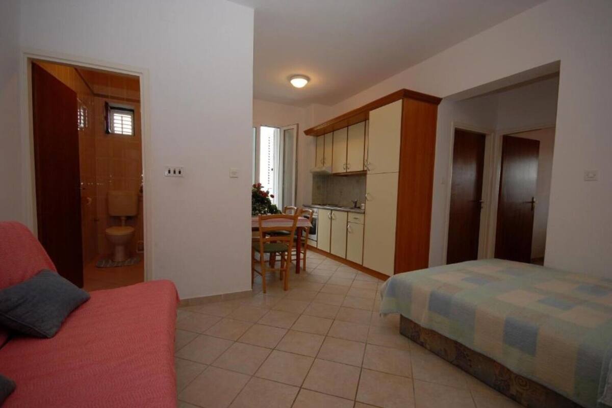 A compact room with a bed, a small kitchenette, a dining area, and a bathroom.