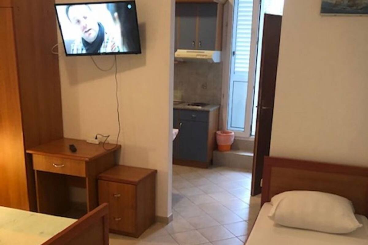 A bedroom with a bed, a desk, a television, and a small cabinet.