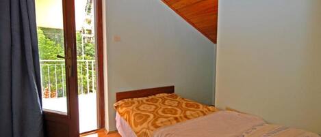 Un dormitorio con cama, techo de madera y balcón con vista a zonas verdes.