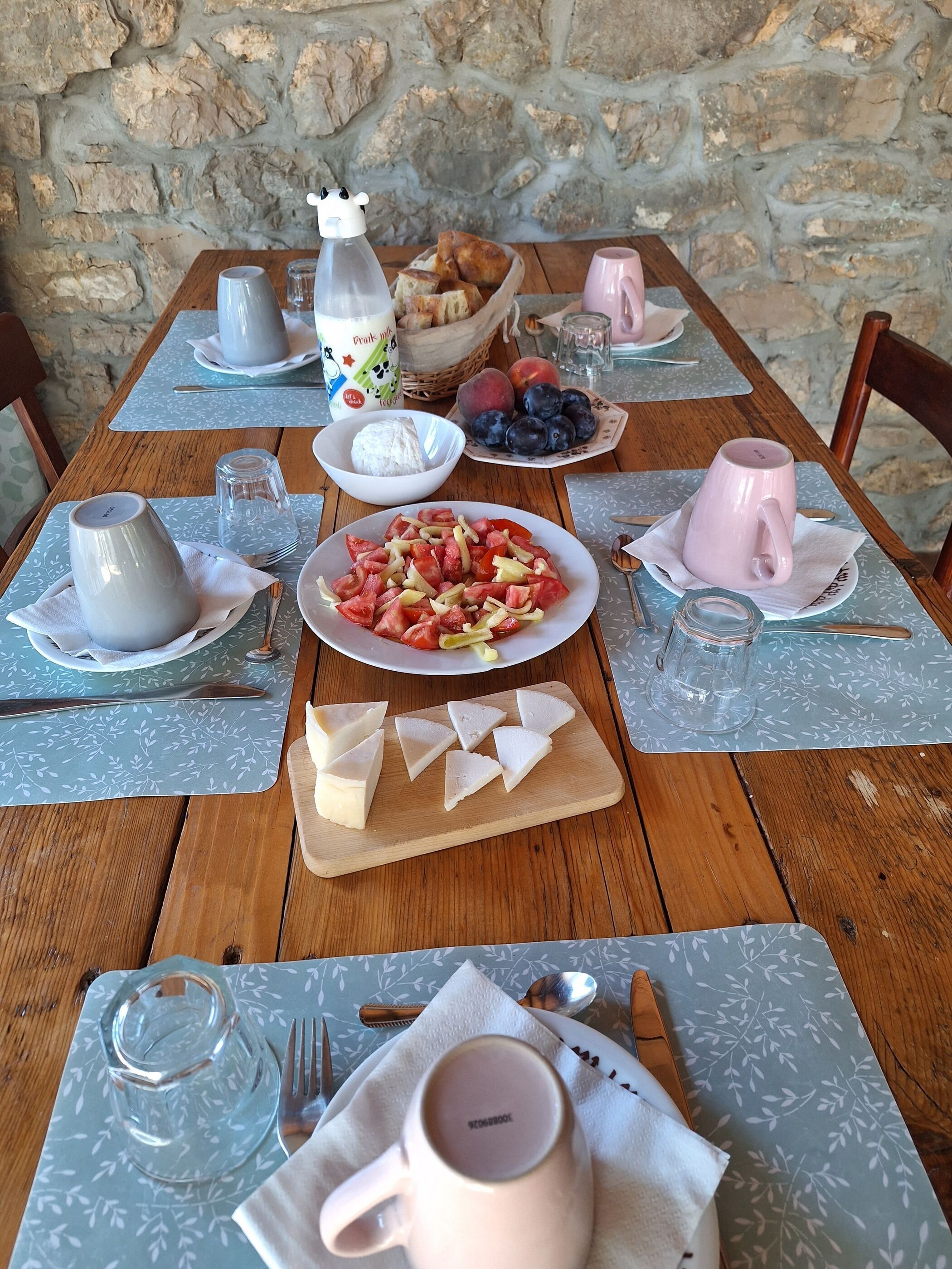 Uma mesa de madeira posta com pratos de comida, um jarro e uma caneca.