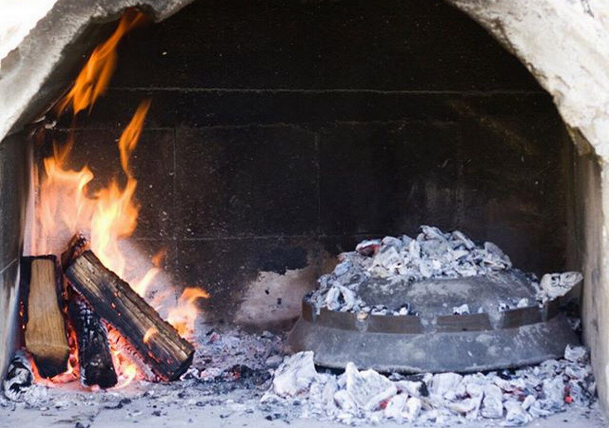 Ein Kamin mit brennenden Holzscheiten und Asche.