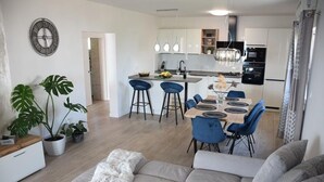 Une cuisine moderne dotée d’un îlot central, de tabourets de bar et d’une table à manger avec des chaises bleues.