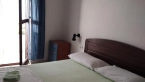 A single-bed room with a wooden headboard, a small bedside table, and a wall-mounted lamp. - Apartments Vlado (Solta)