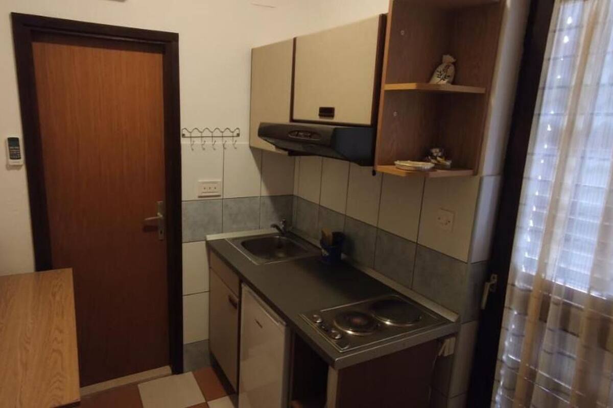 A compact kitchen with a wooden bench, a sink, and a stove.