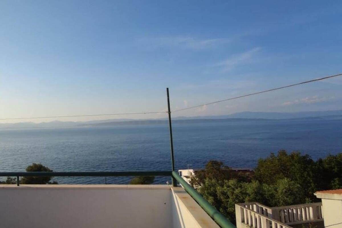 A balcony with a view of the sea and distant mountains.